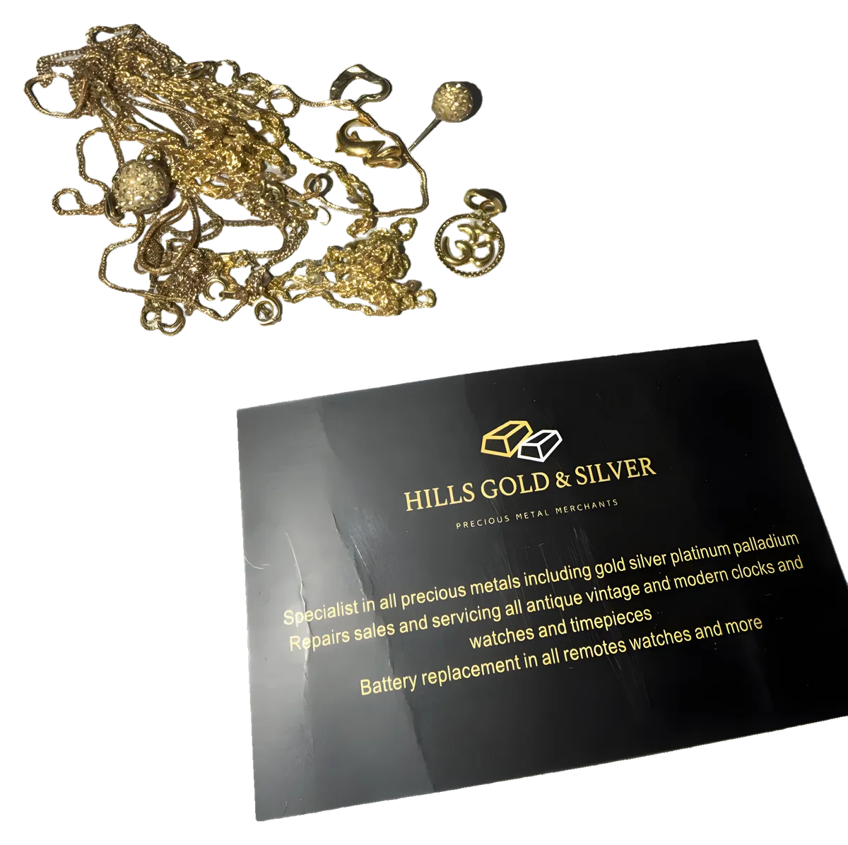 Gold chains on the counter beside a Hills Gold & Silver card